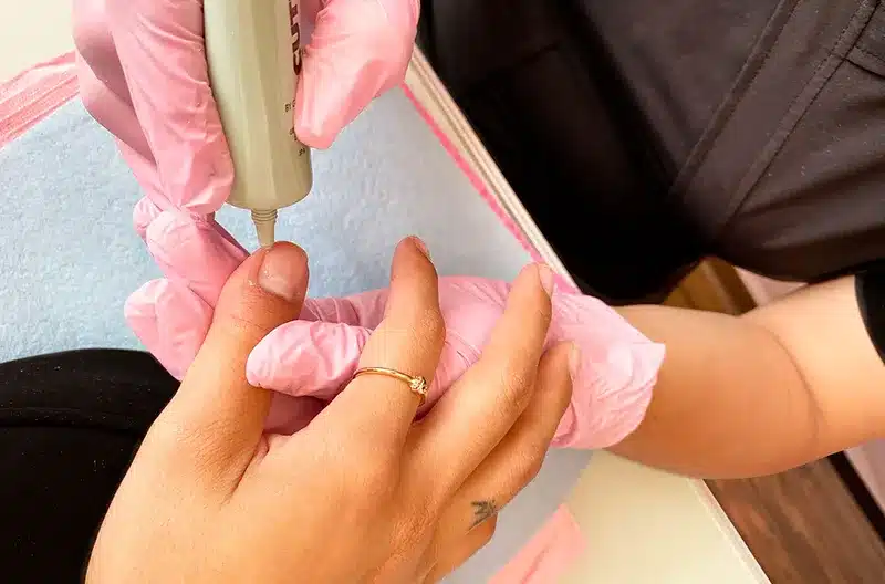 Profesional de la belleza dando servicio a las uñas de una mujer - Diann Studio